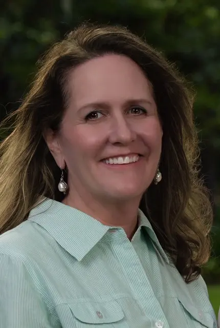 A woman with long hair wearing a green shirt.