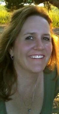 A woman smiling for the camera with long hair.