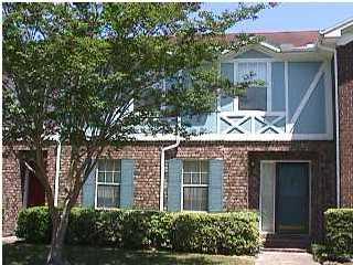 A blue brick house with a tree in front of it.